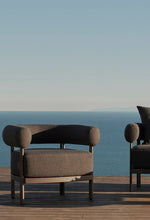 Load image into Gallery viewer, Rocchetto outdoor chair taupe boucle — waterfront landscape — full sculptural form visible — Minosé
