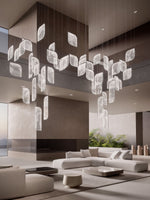 Load image into Gallery viewer, Foglia large chandelier — double-sided configuration in light finish — suspended over modern interior with cream seating — Minosé
