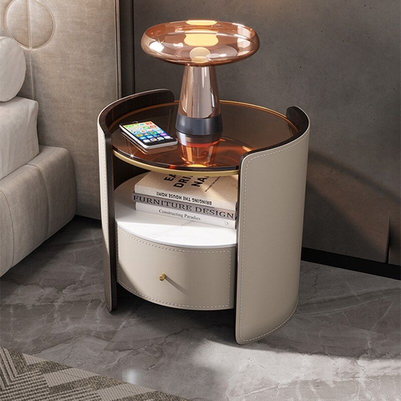 Luxury bedside table with smoked glass top, curved leather panels, and drawer storage by Minosé